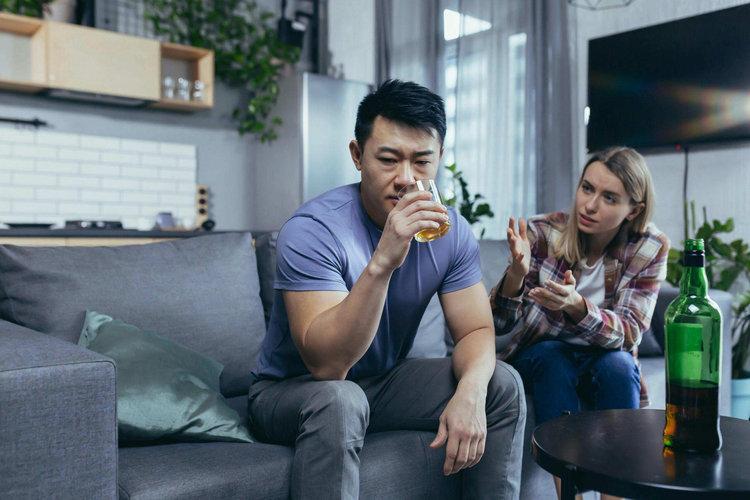 alcoholic husband sitting on couch with concerned wife