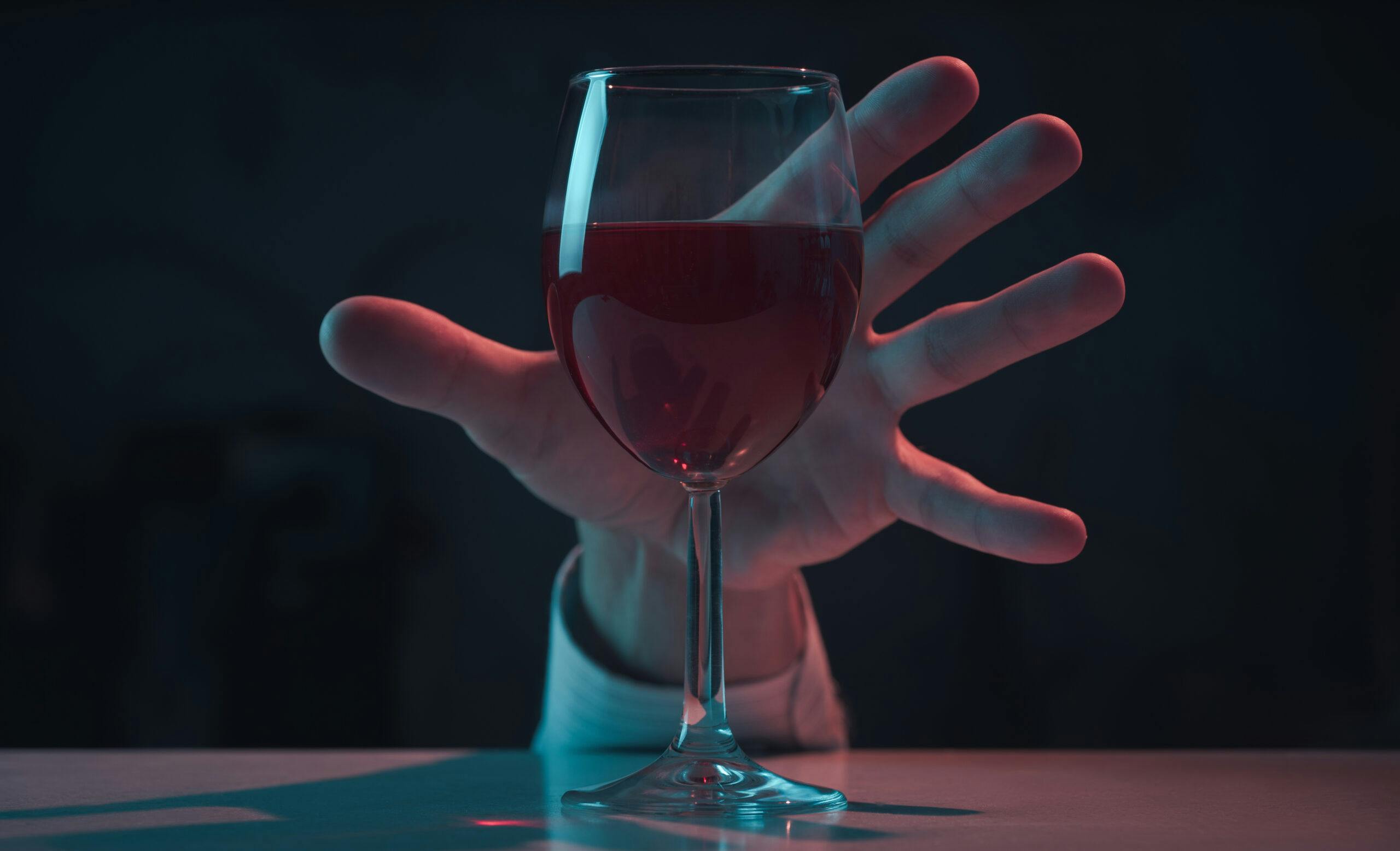 alcoholic man reaching hand for wine glass