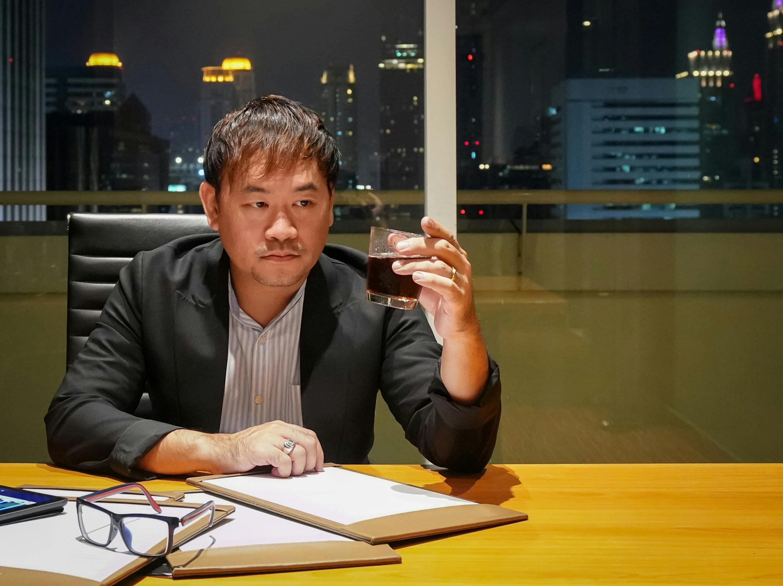 asian businessman drinking liquor in high rise city building