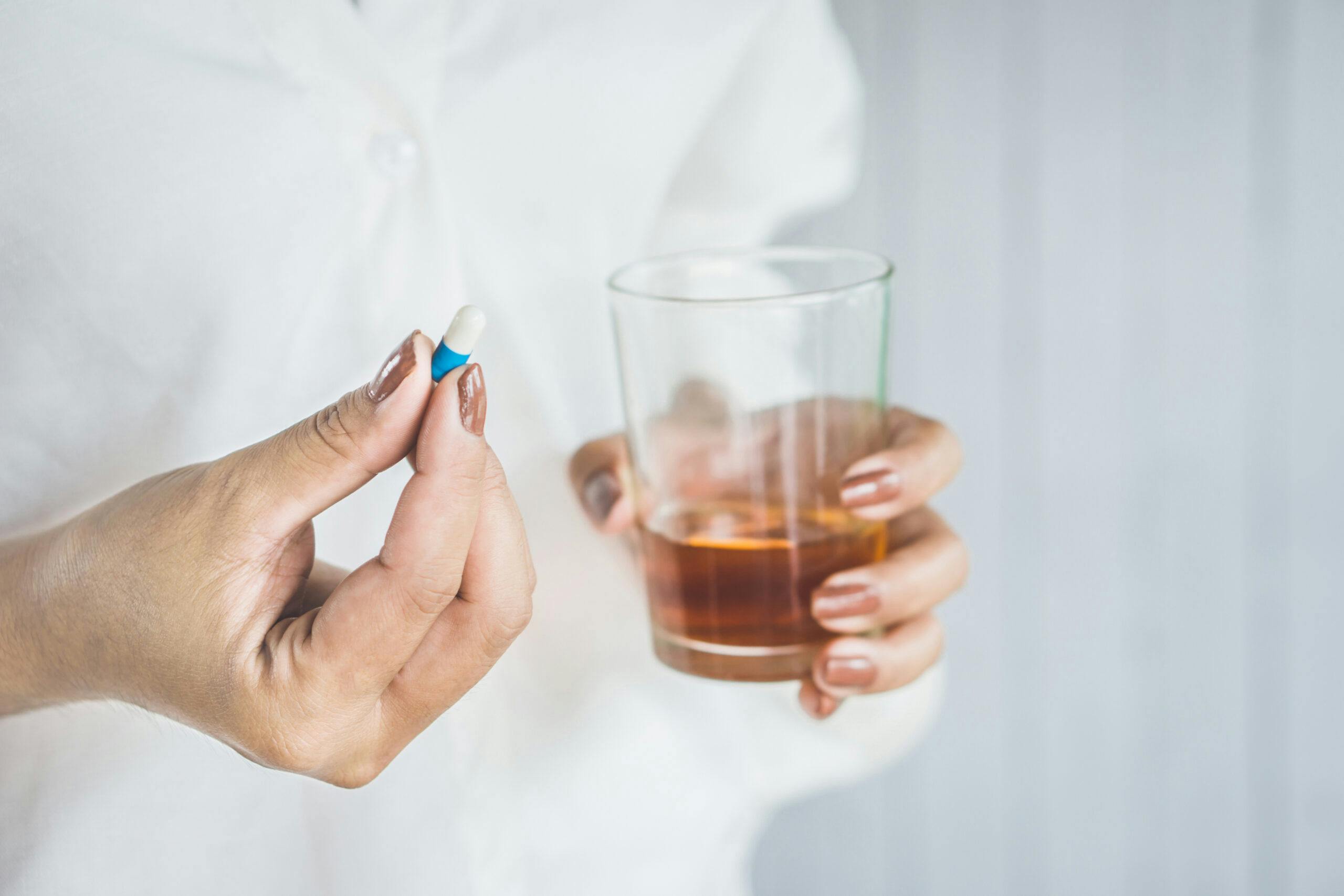 woman taking prescription pill with liquor