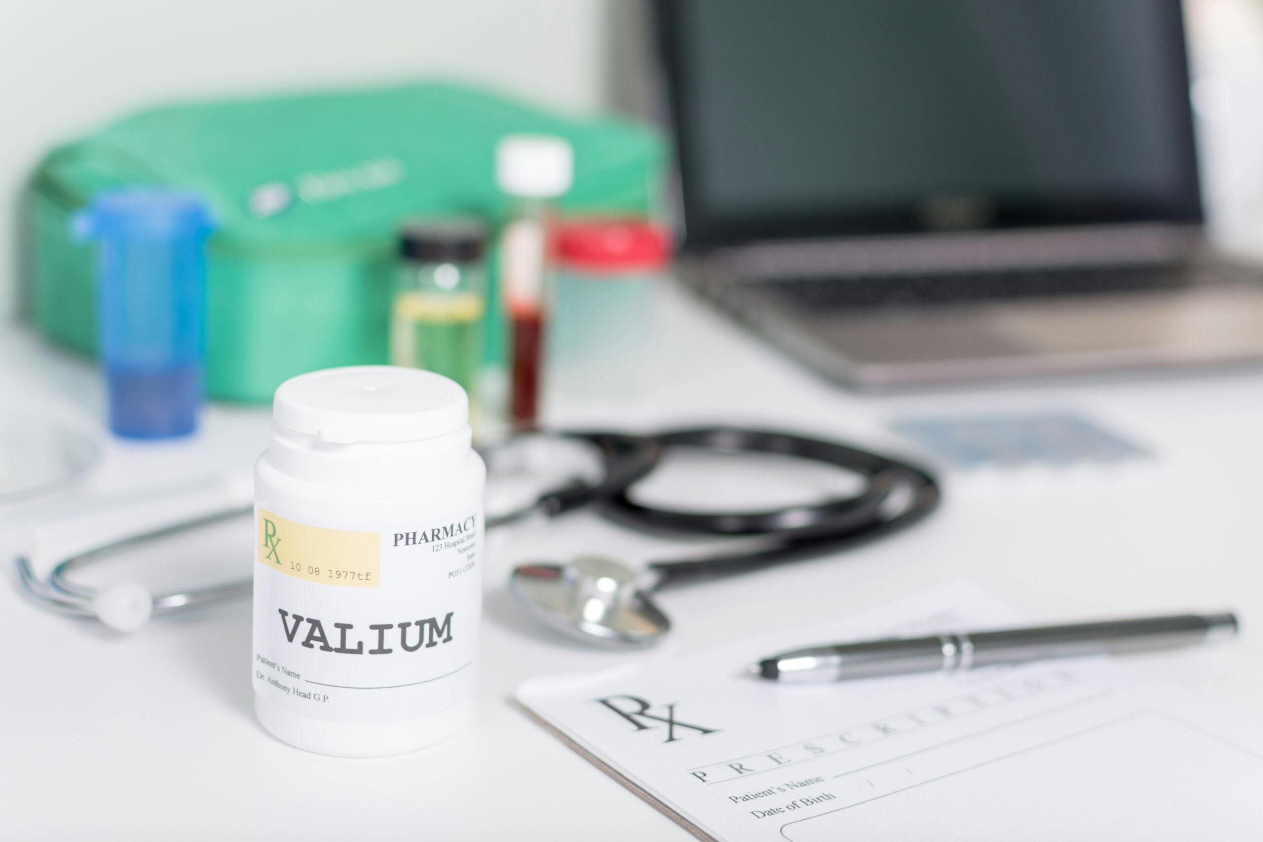 doctor's desk with valium bottle vials stethoscope laptop