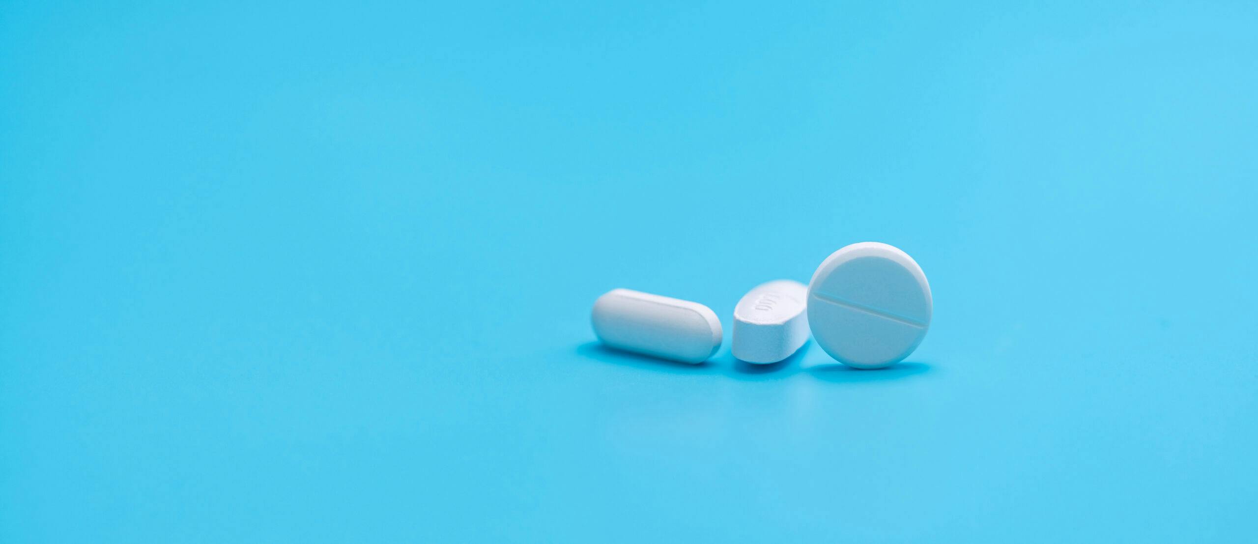 white round oblong white pills on blue table