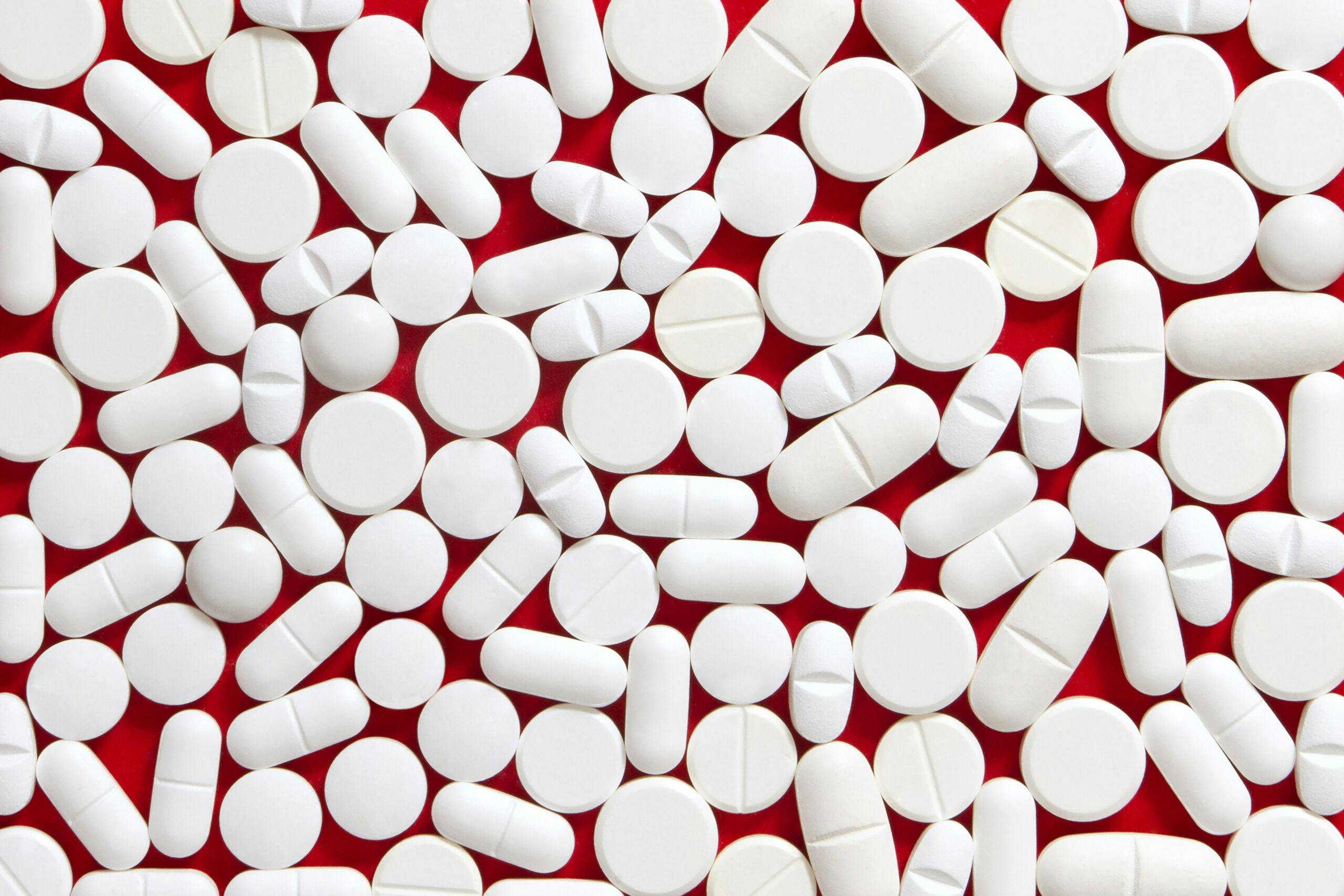 assortment of white pills on red background