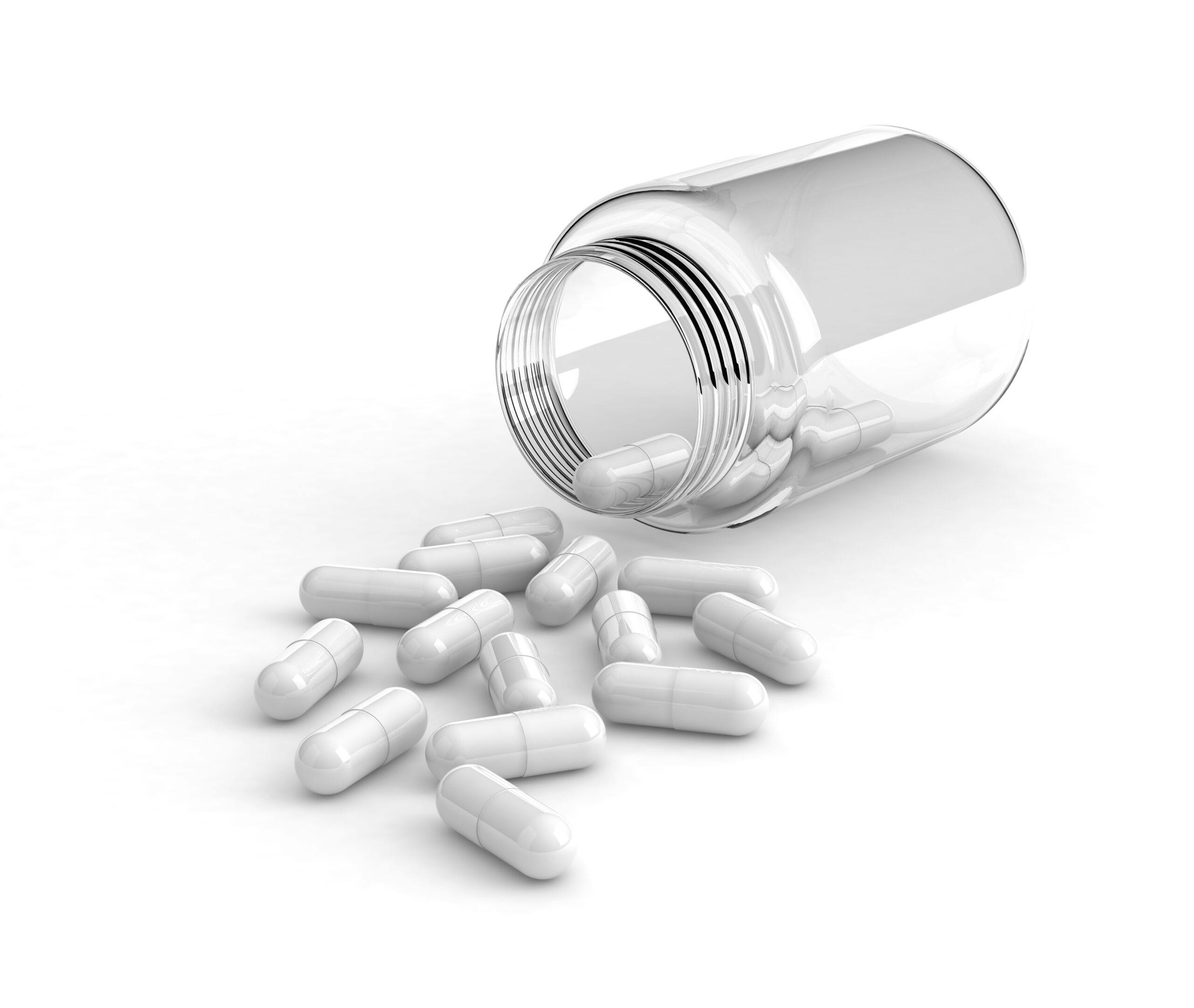 white pill capsules and glass bottle