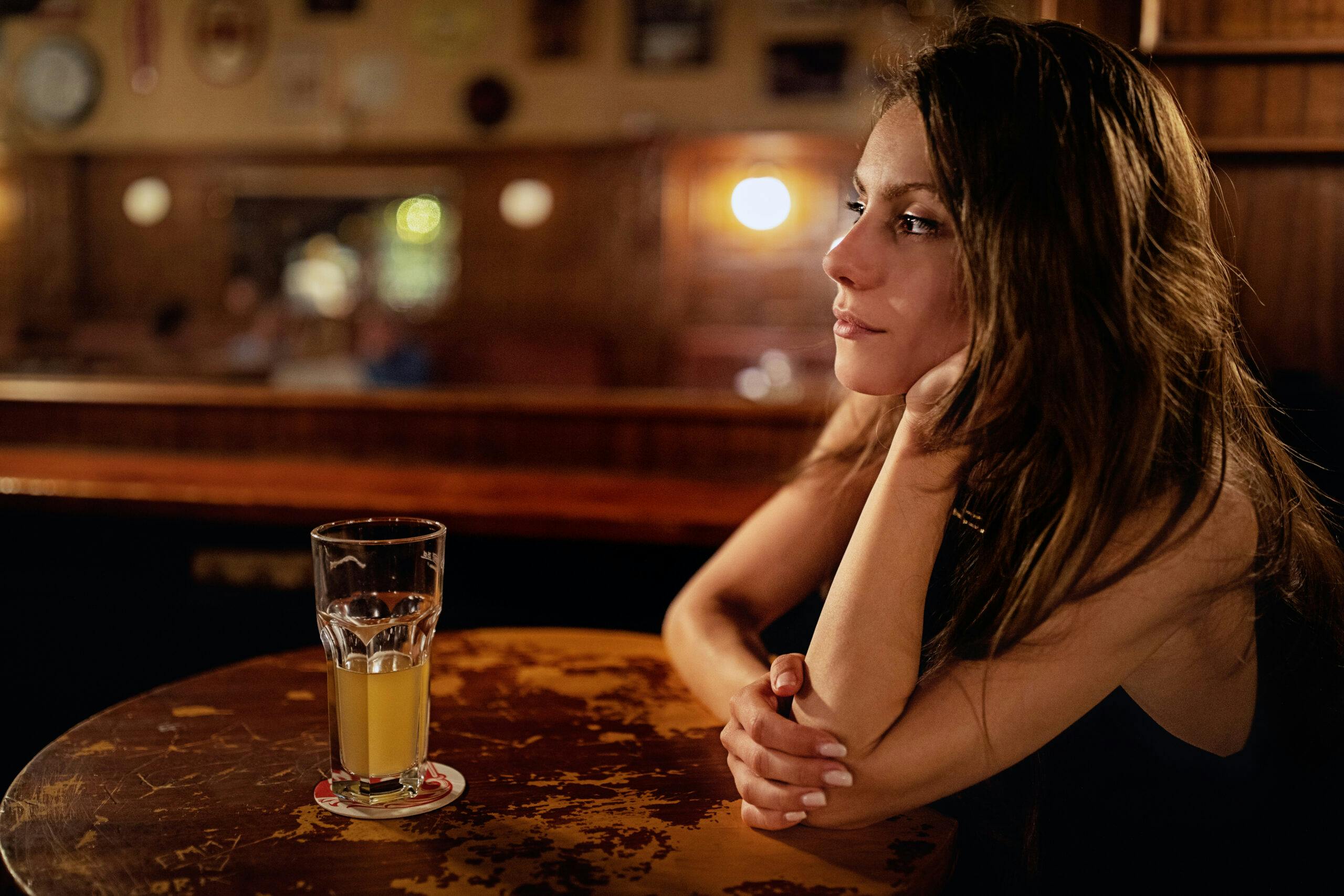 depressed woman drinking beer at bar