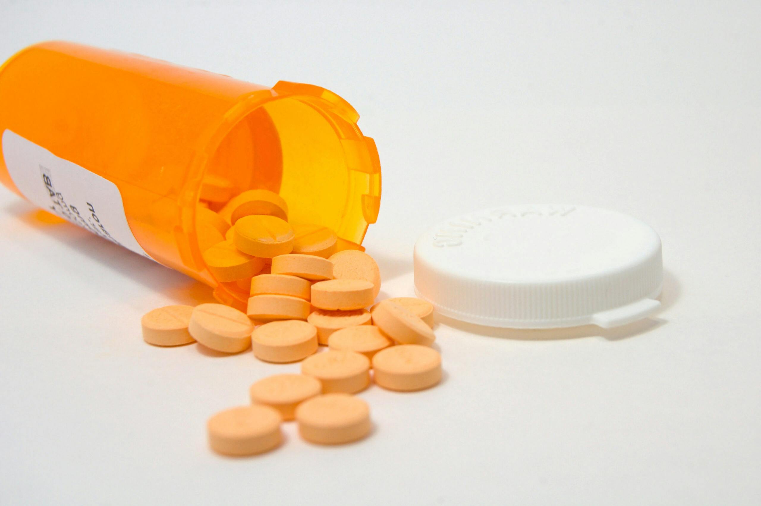 prescription bottle with orange pills spilling out