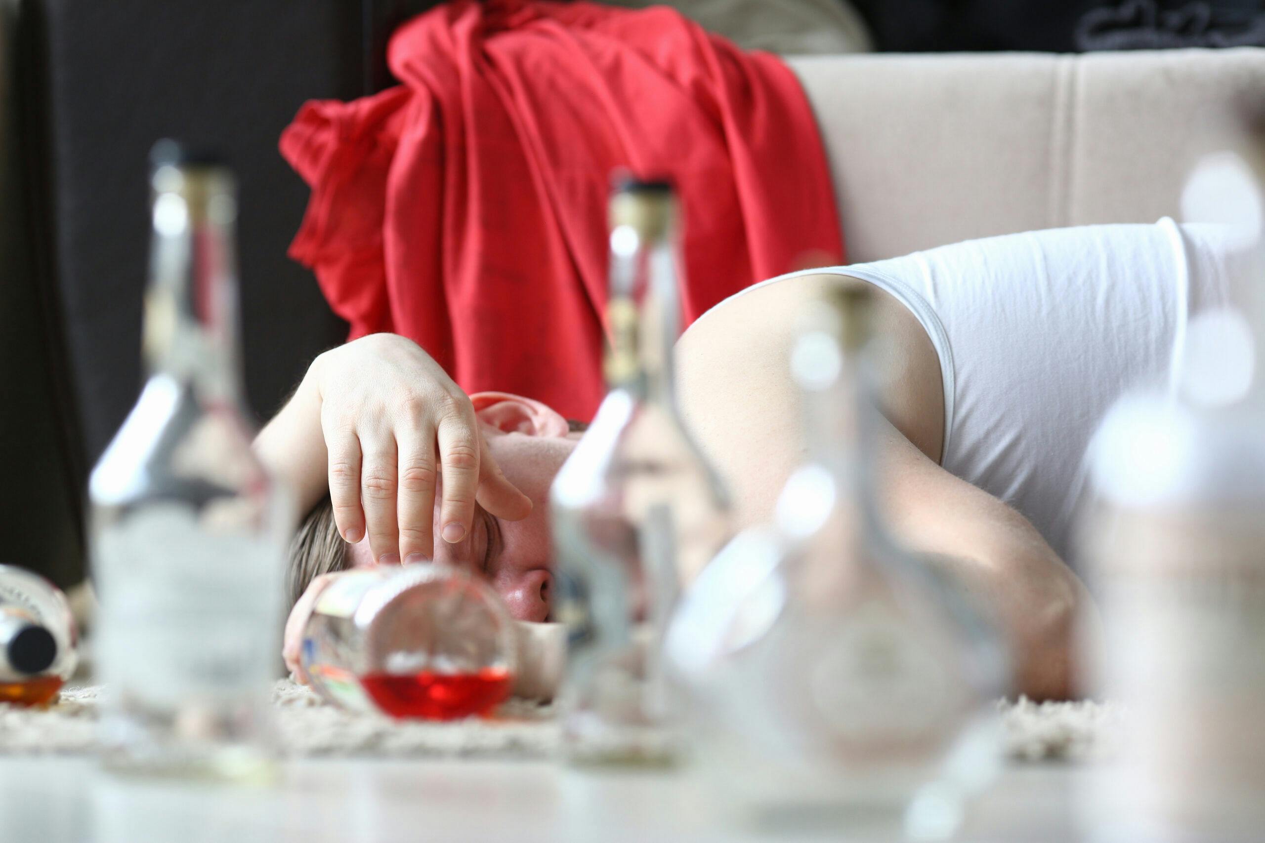 drunk hungover alcohol overdose man with empty liquor bottles