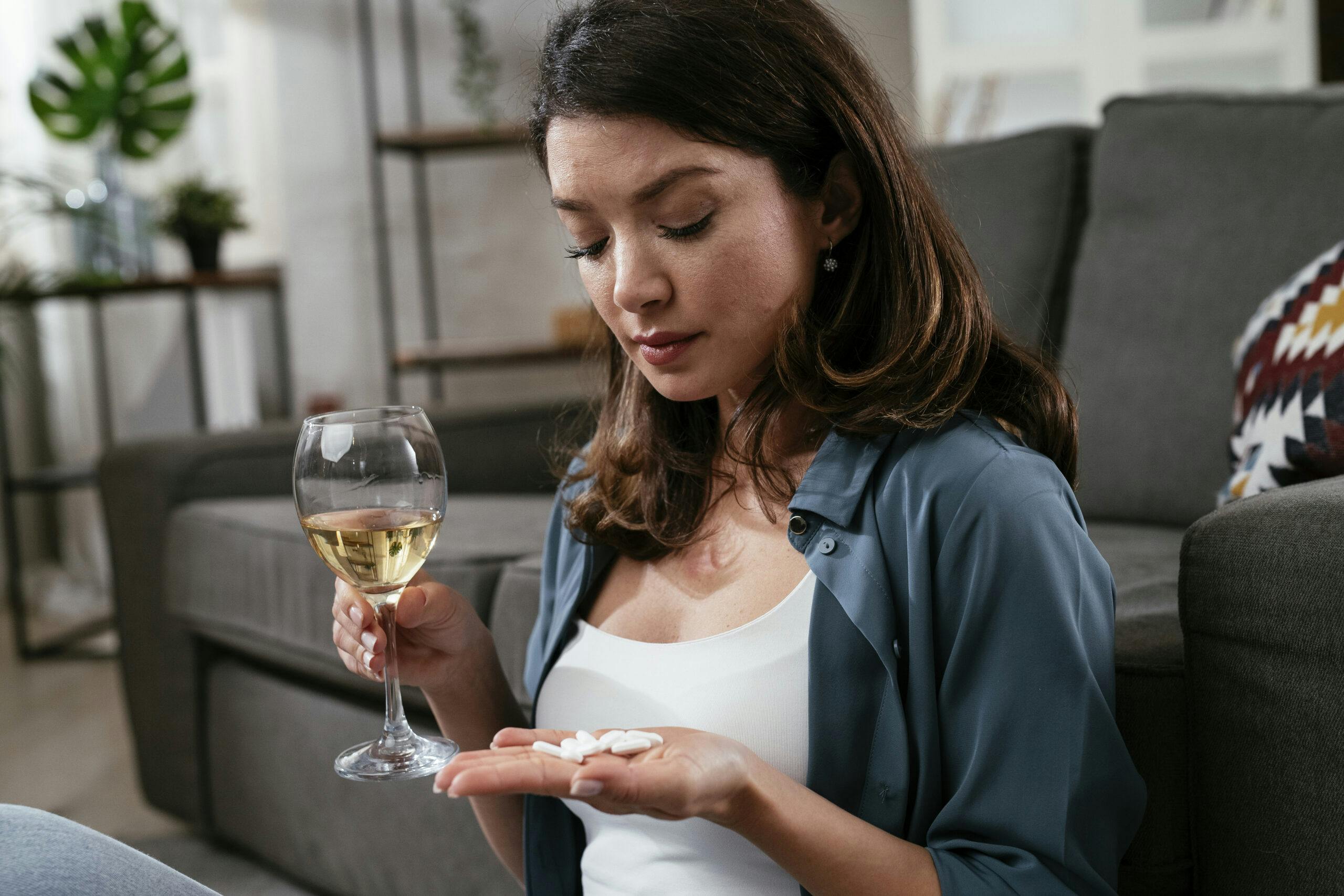 woman drinking wine and taking white pills lortab