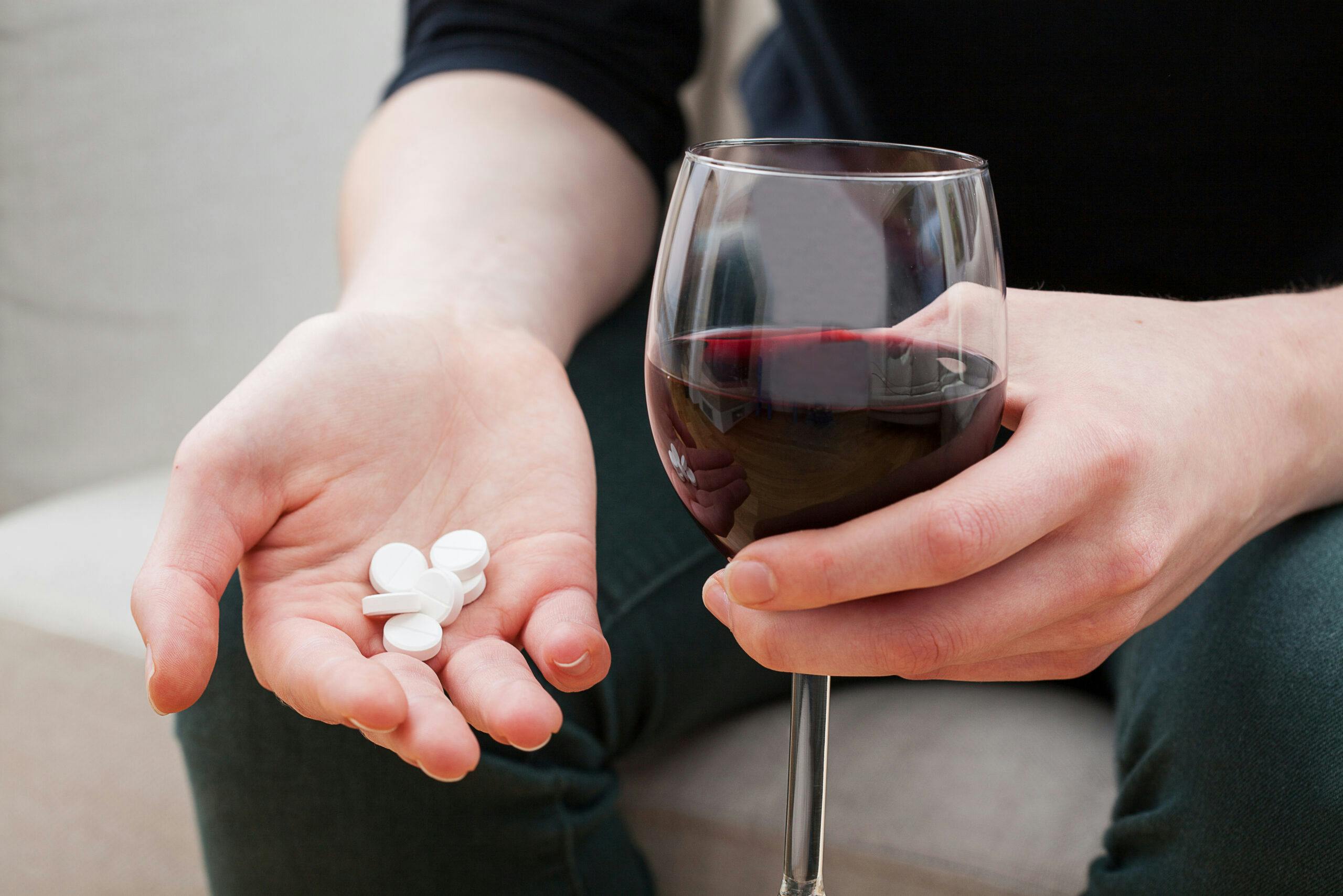 woman taking percocet pills with wine
