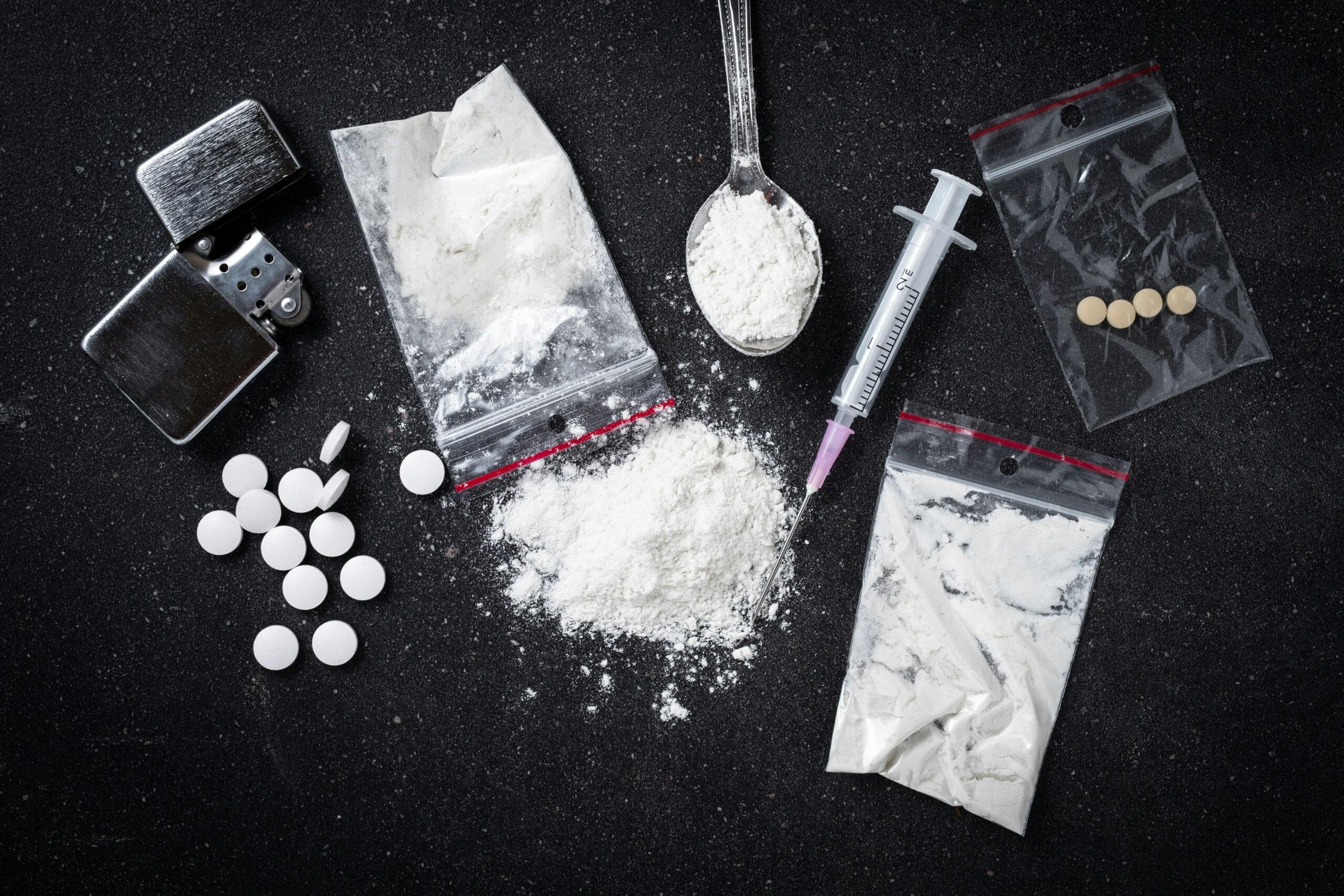 white powder pcp drugs on table with needle baggie pills