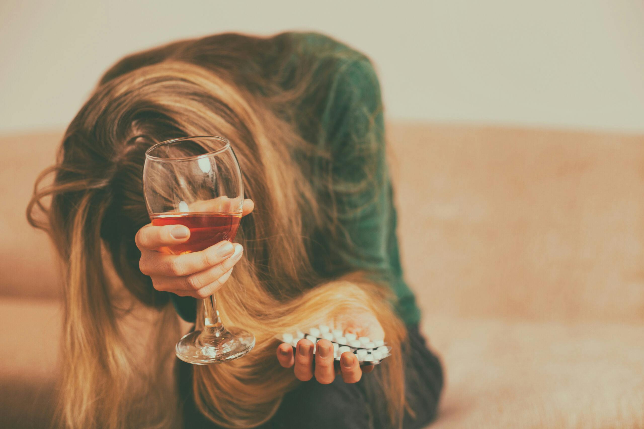 depressed woman sick drinking wine taking pills phenibut