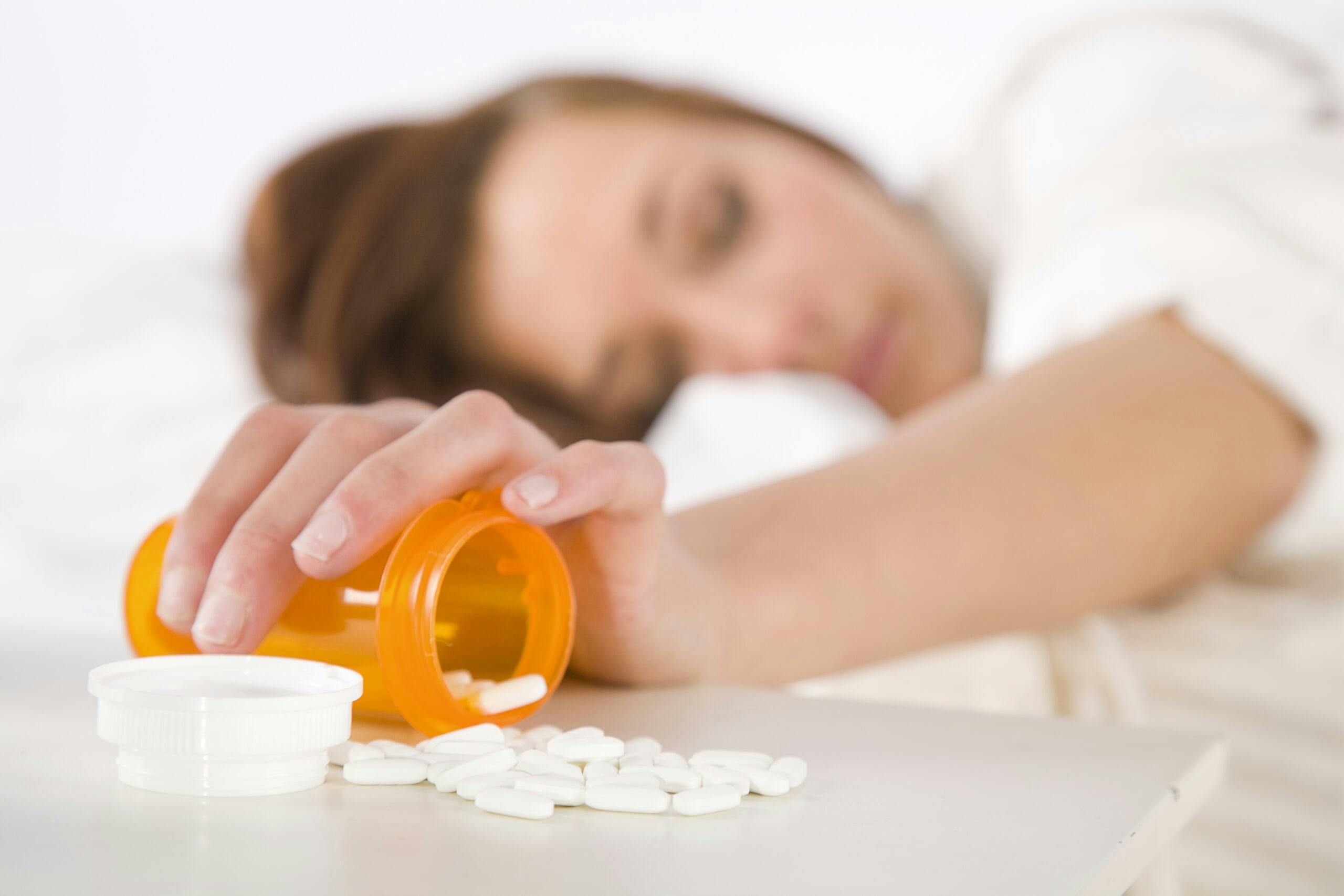 young woman sleeping bottle of white pills gabapentin
