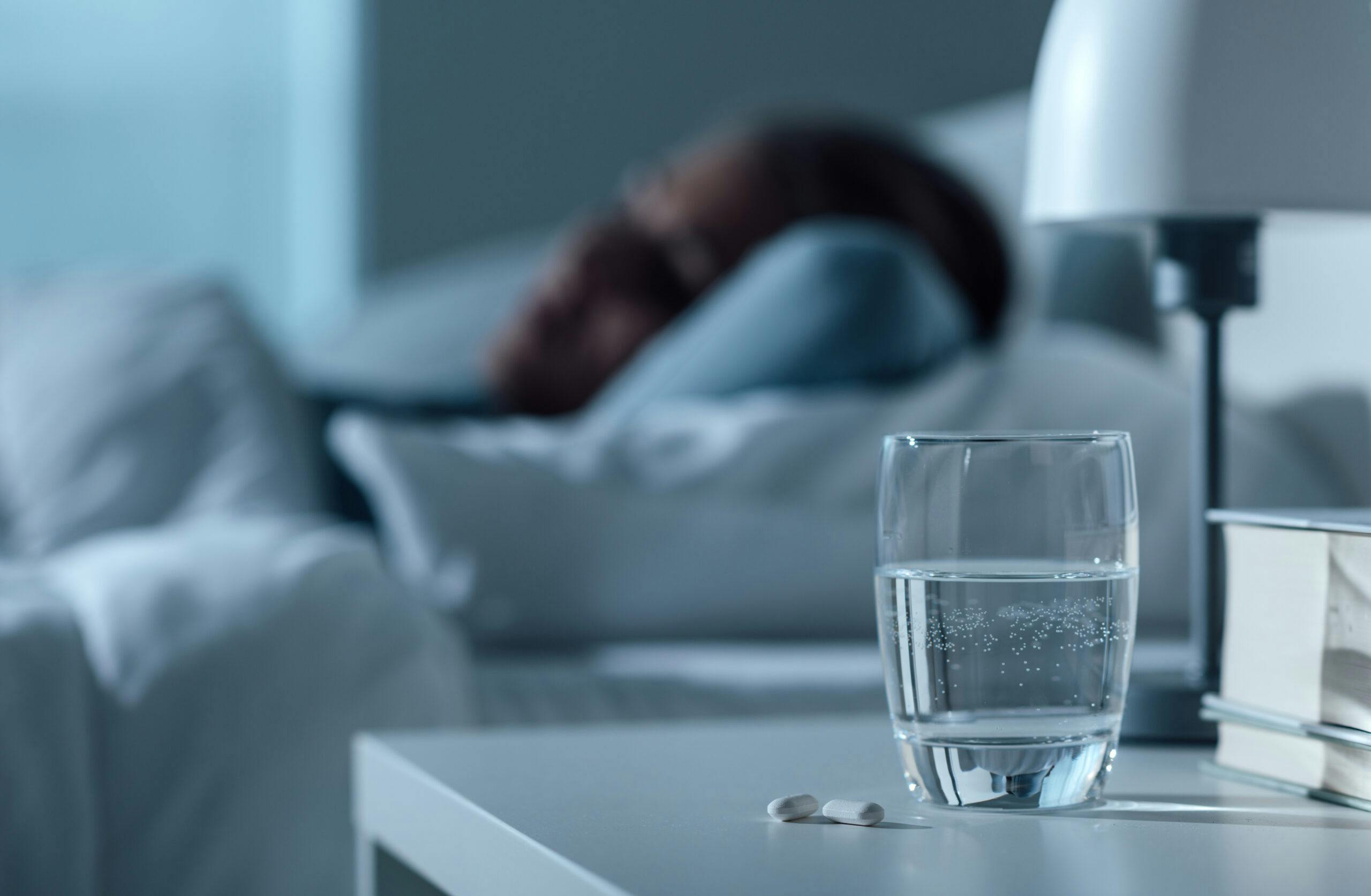 woman sleeping in bed next to water glass and pills klonopin