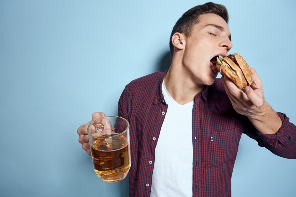 drunk man eating burger holding beer