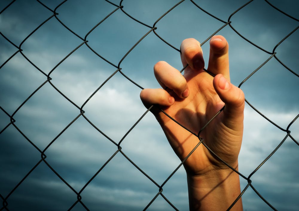 hand behind jail chain link fence