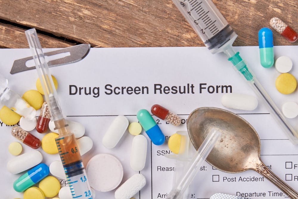 drug screen results form with pills needle spoon