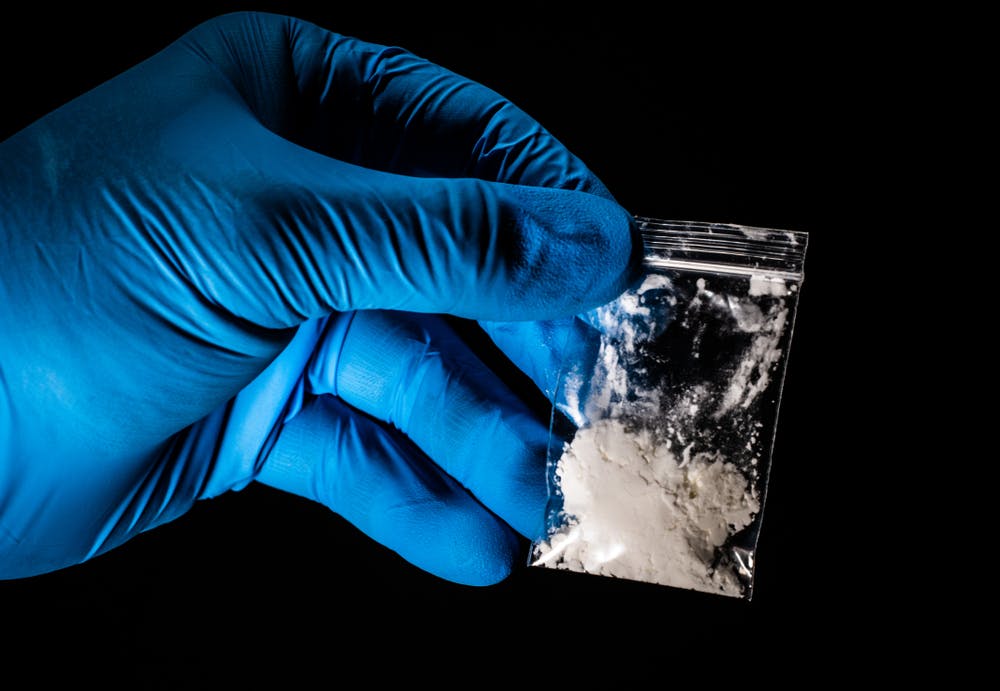 gloved hand holding bag of fentanyl