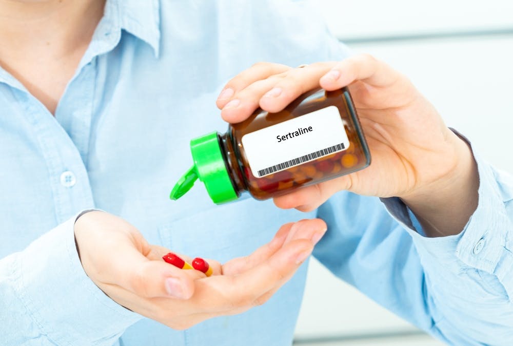 woman pouring sertraline out of bottle