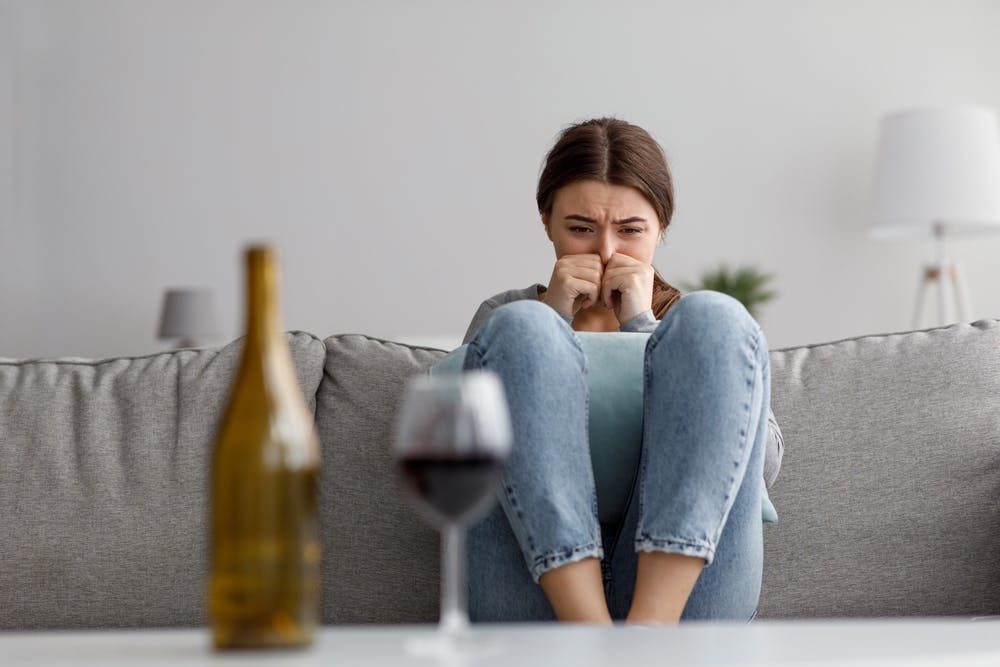 woman crying on couch with wine bottle