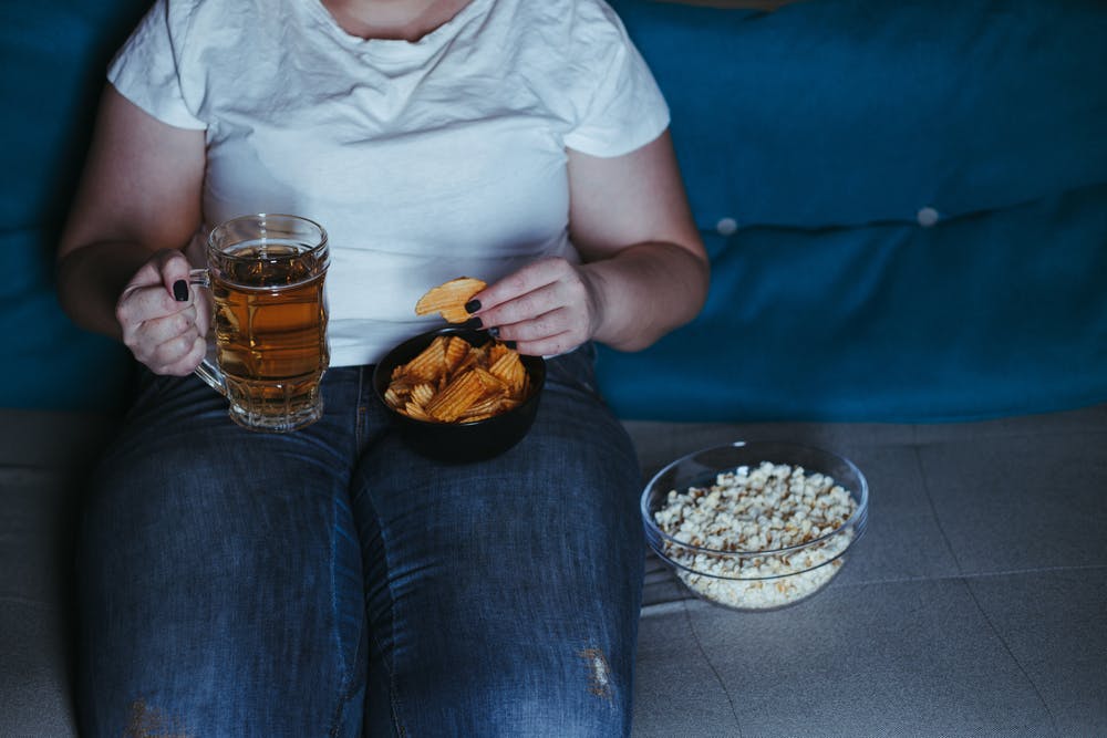 woman overeating snacks drinking beer