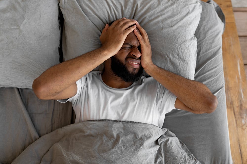 man hungover in bed anxious