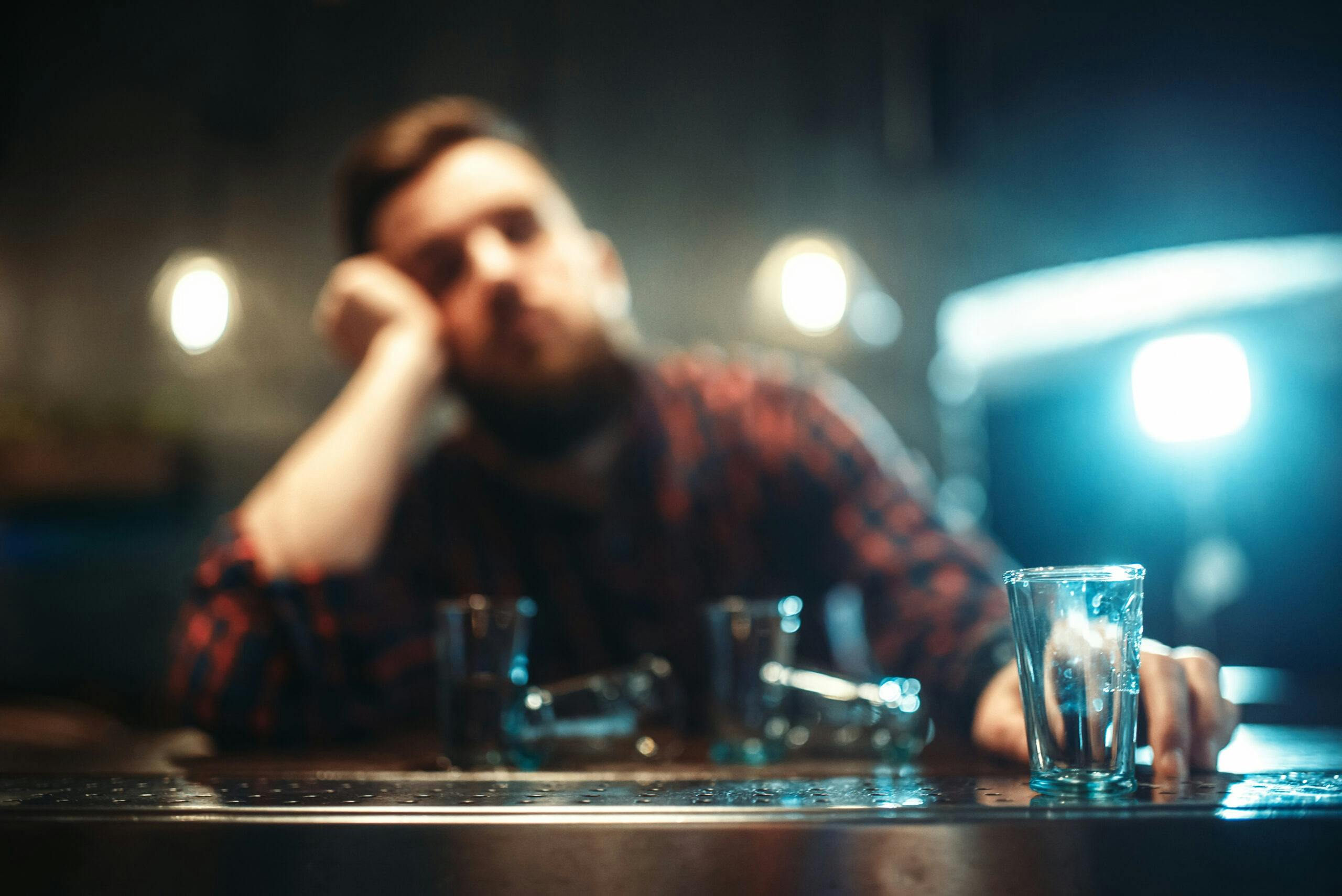 man with empty shot glasses at bar