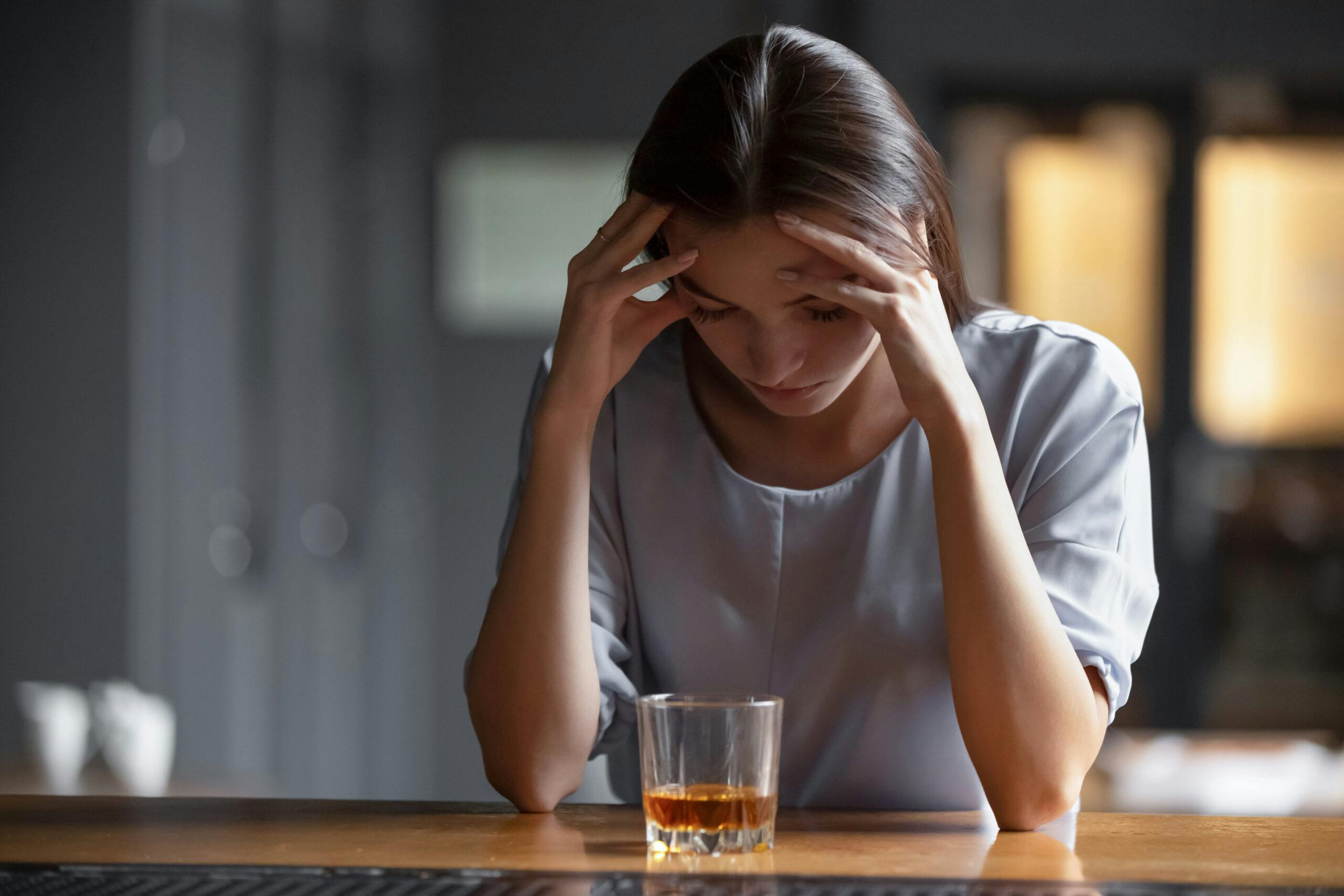 anxious woman at bar with liquor