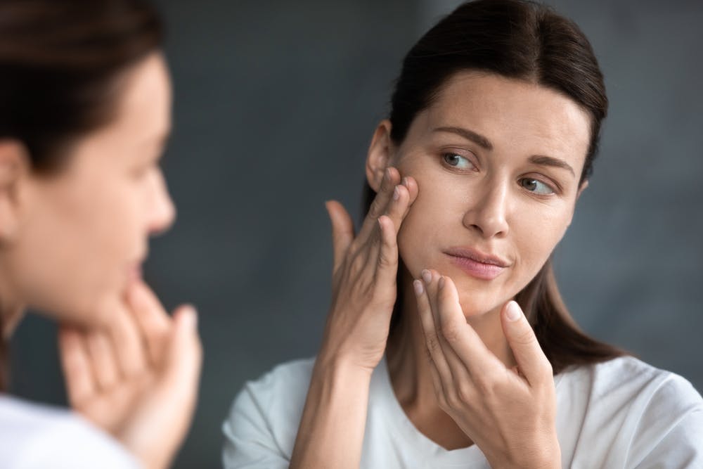 woman in mirror looking at bad skin alcoholic