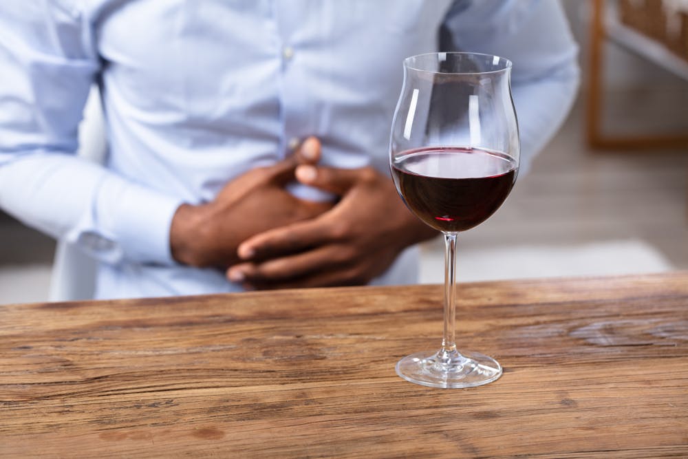 man holding stomach after drinking red wine
