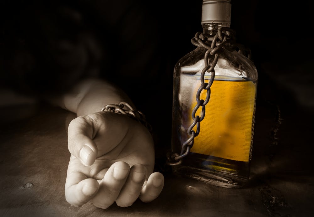 hand chained to alcohol bottle