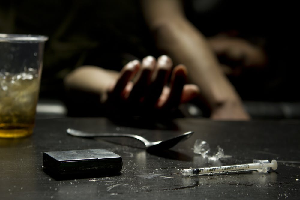 man passed out with alcohol and drugs syringe