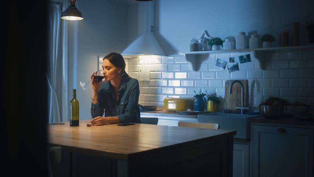 woman drinking wine in kitchen at night