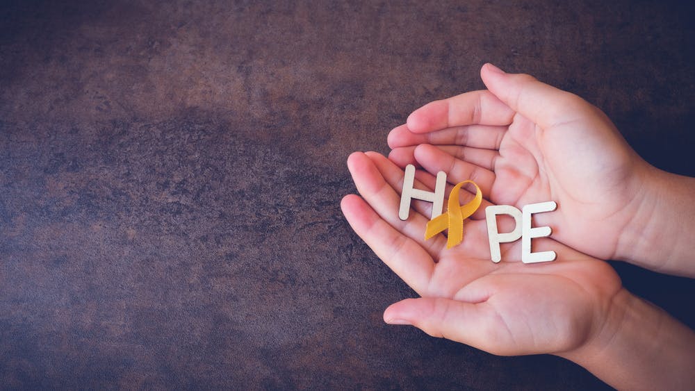 hope in hands with yellow ribbon