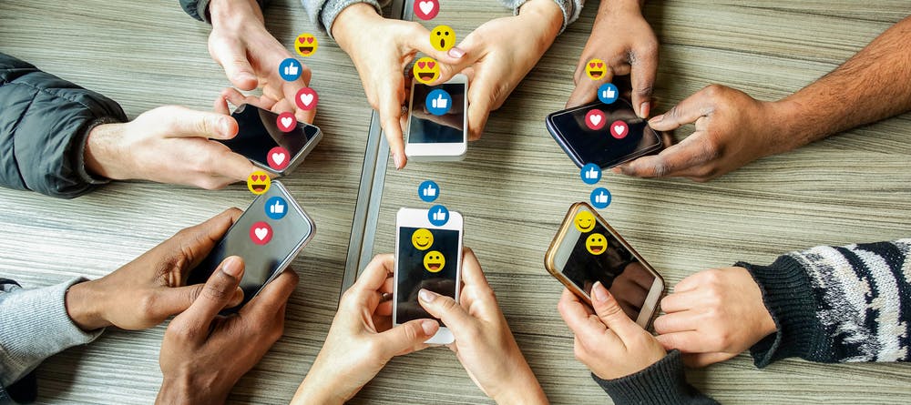 group of people with phones in hands and emojis likes
