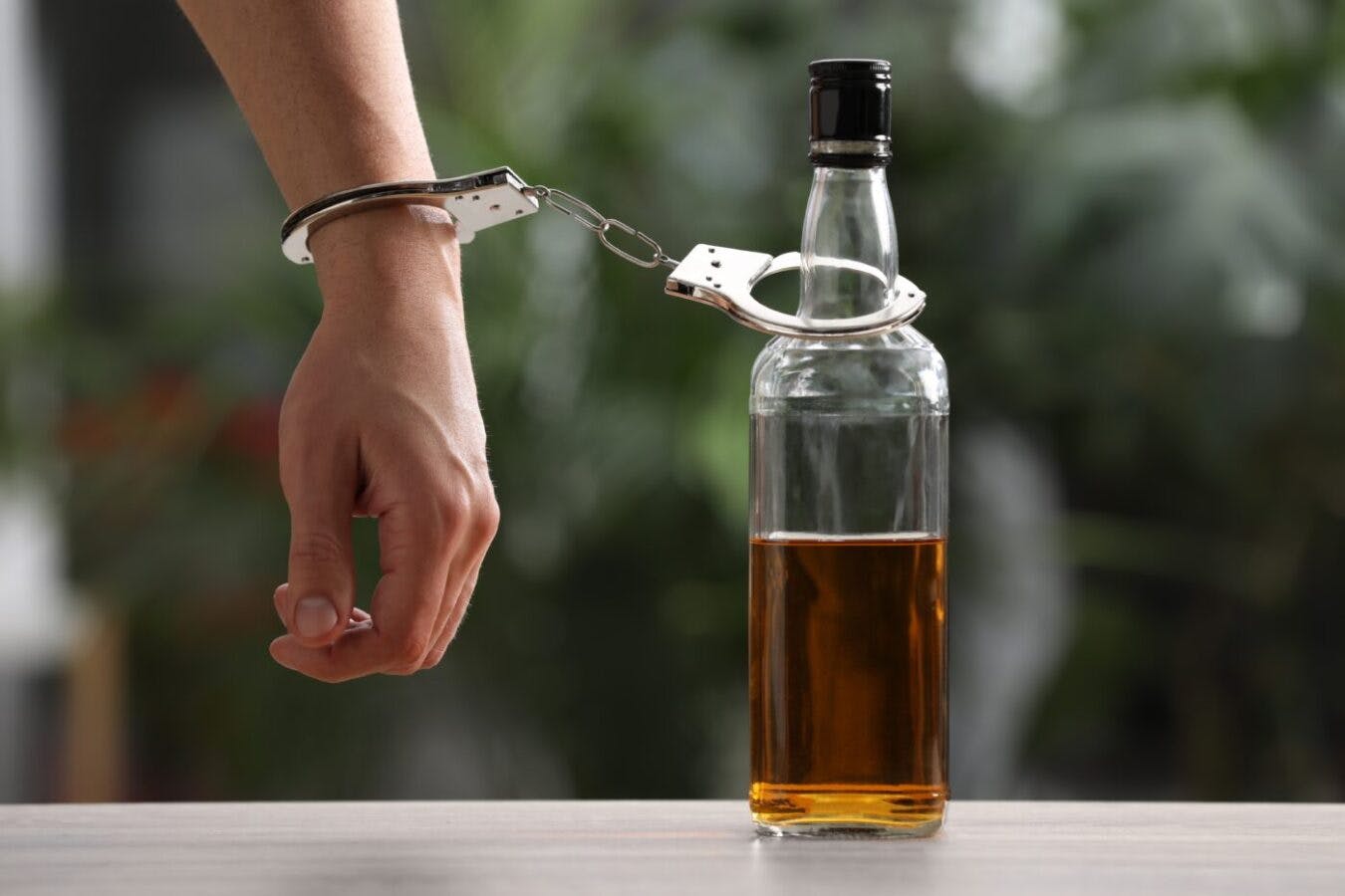 man handcuffed to liquor bottle