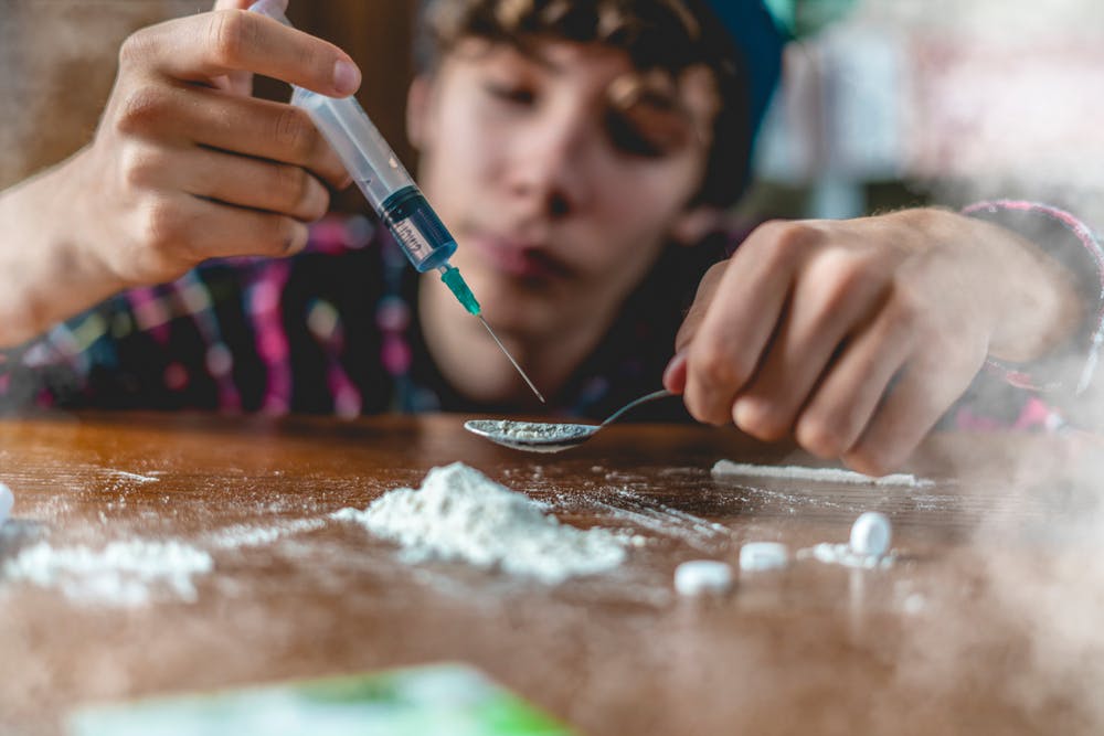young drug addict preparing white powder drugs with needle